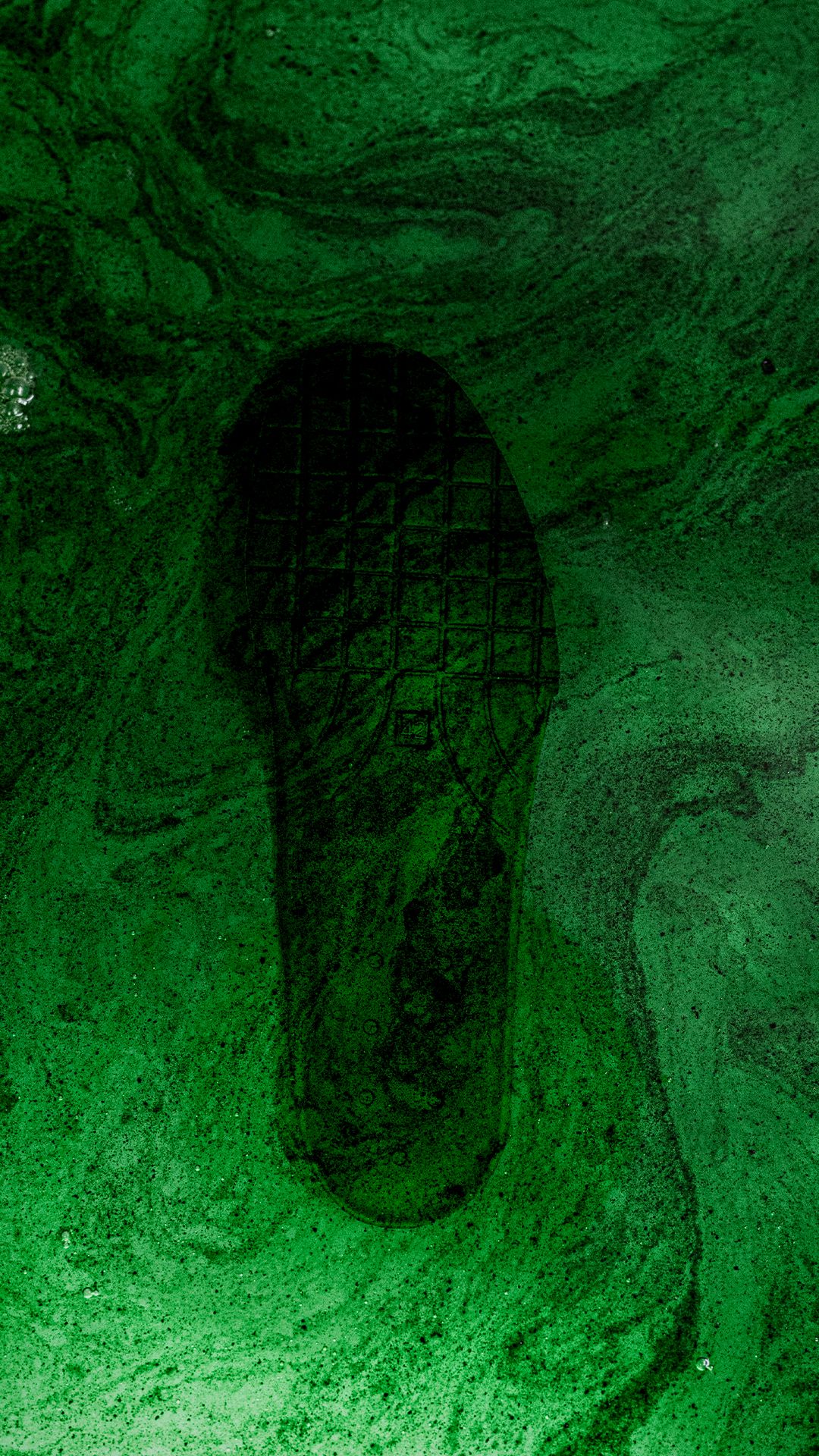 A dark shoe print is visible on a textured green surface, resembling swirling patterns of marbled paint.
