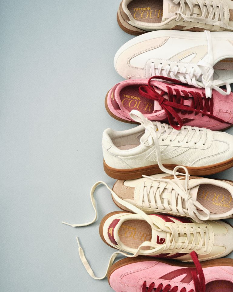 A vertical row of colorful sneakers with visible laces on a light gray background. The sneakers are white, pink, and red.